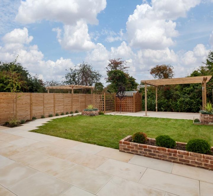 landscape of a new house garden with raised beds, stone patio, pergola and deck on the background