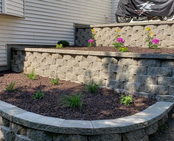 layer of block retaining walls with new flower shrubs, and top soil