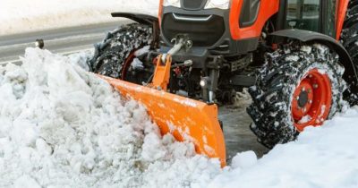 closeup of a small tractor plowing snow on the highway